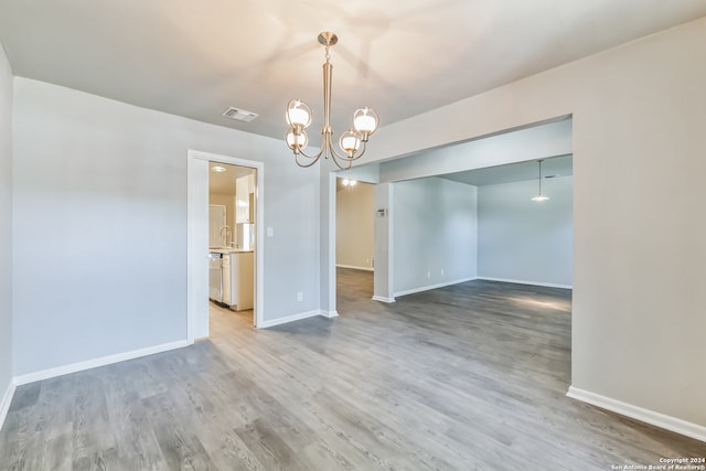 unfurnished room featuring an inviting chandelier and hardwood / wood-style flooring