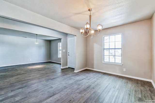 unfurnished room featuring a textured ceiling, a chandelier, and dark hardwood / wood-style flooring