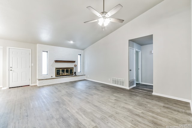 unfurnished living room with a brick fireplace, hardwood / wood-style floors, ceiling fan, and vaulted ceiling