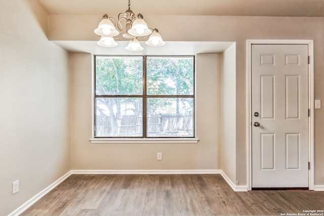 spare room featuring a notable chandelier and wood-type flooring