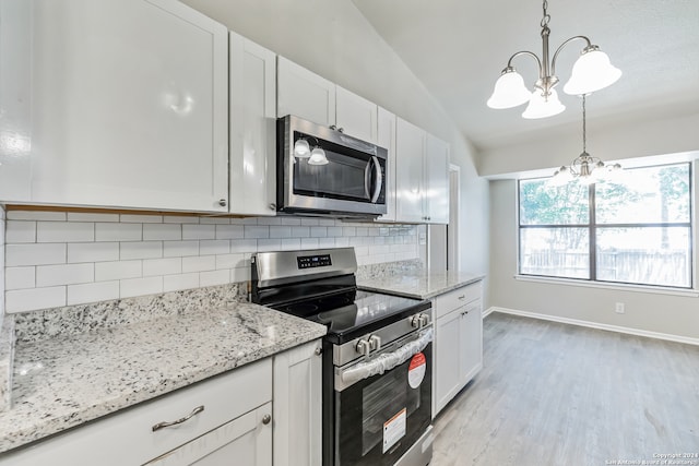 kitchen with tasteful backsplash, white cabinetry, a chandelier, vaulted ceiling, and stainless steel appliances