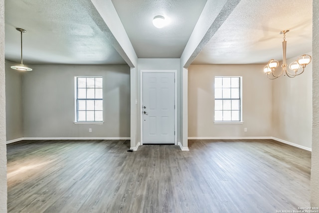 foyer featuring a wealth of natural light, a textured ceiling, a notable chandelier, and hardwood / wood-style flooring