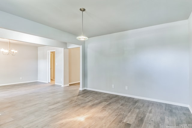 spare room featuring hardwood / wood-style flooring and an inviting chandelier