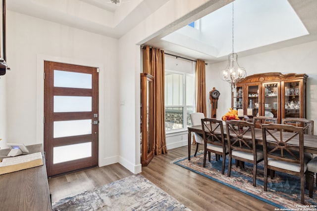 dining room with a notable chandelier, wood-type flooring, and a raised ceiling