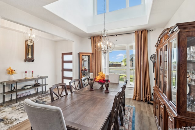 dining space with light hardwood / wood-style floors, a notable chandelier, and a tray ceiling