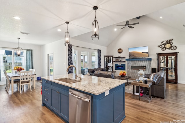 kitchen with hanging light fixtures, an island with sink, blue cabinetry, a fireplace, and sink