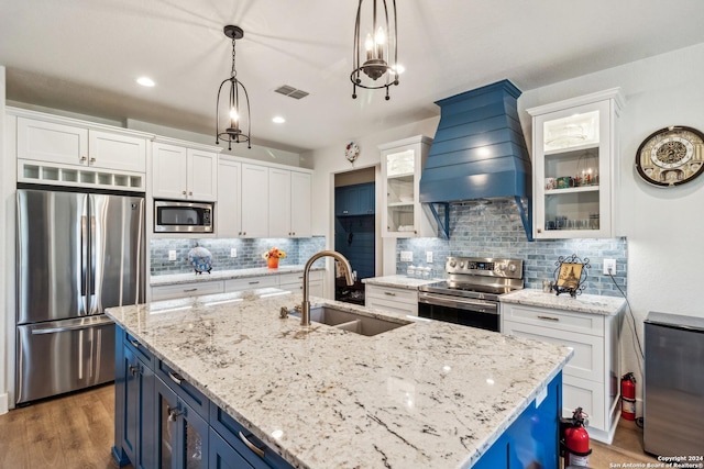 153 W Magnolia Cir, La Vernia, TX 78121 - kitchen featuring stainless steel appliances, a sink, custom range hood, blue cabinetry, and white cabinets