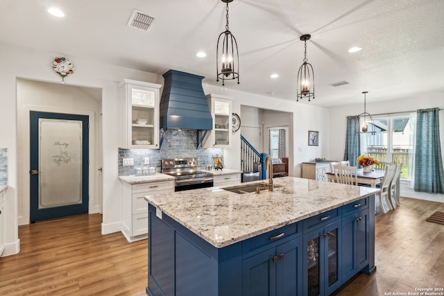 kitchen featuring electric stove, blue cabinetry, pendant lighting, and white cabinets