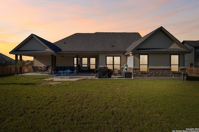 back house at dusk featuring a yard, a patio area, and central AC unit