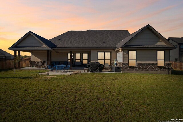 153 W Magnolia Cir, La Vernia, TX 78121 - back of property at dusk with a patio, brick siding, and central air condition unit