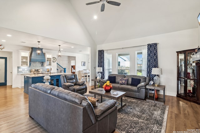 living room featuring ceiling fan, high vaulted ceiling, sink, and hardwood / wood-style floors