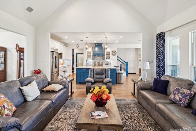 living room with high vaulted ceiling and light hardwood / wood-style flooring