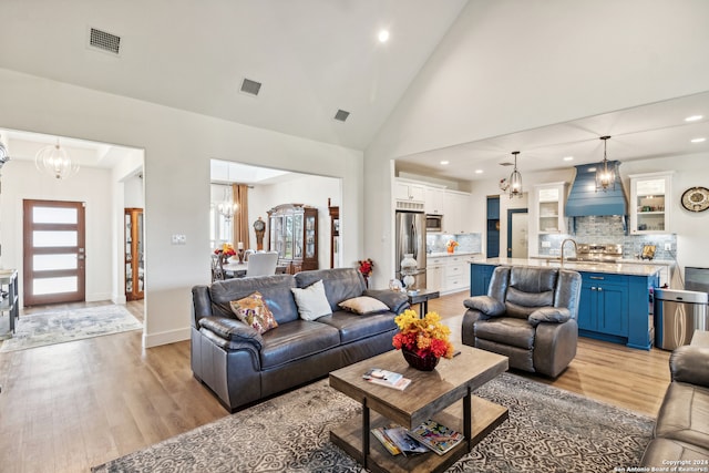 living room with sink, high vaulted ceiling, and light hardwood / wood-style flooring