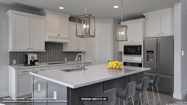 kitchen with a center island with sink, sink, black appliances, decorative light fixtures, and white cabinets