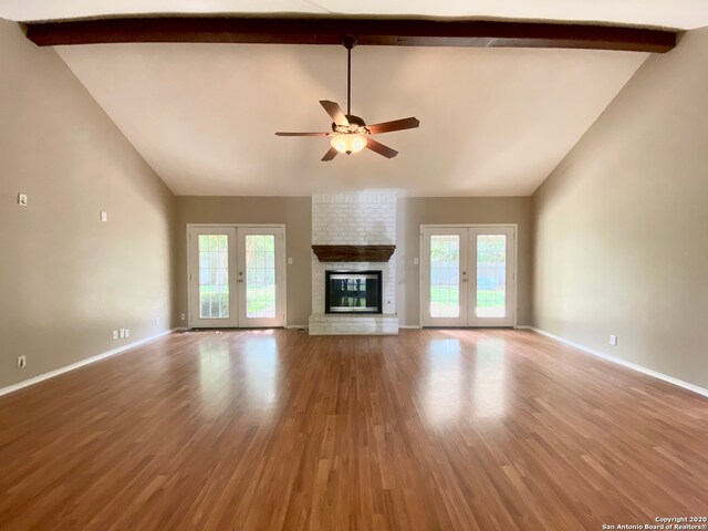 unfurnished living room featuring french doors, beam ceiling, wood-type flooring, and plenty of natural light