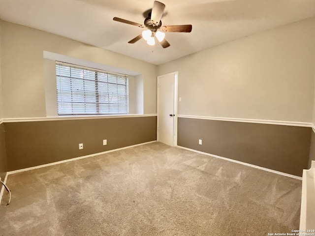 carpeted empty room with ceiling fan and baseboards