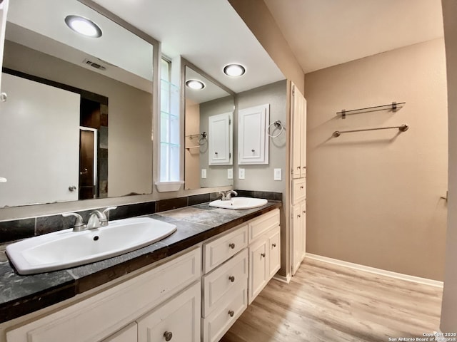 bathroom with wood finished floors, double vanity, and baseboards