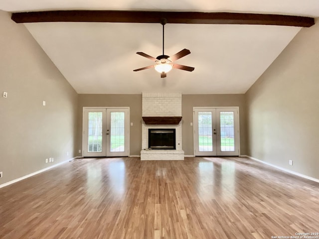unfurnished living room featuring french doors, ceiling fan, beam ceiling, a fireplace, and high vaulted ceiling
