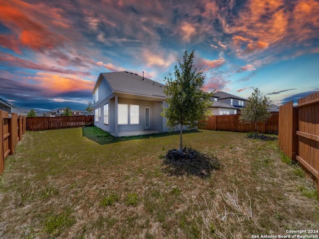 back house at dusk featuring a yard