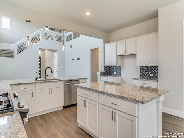 kitchen with sink, a center island, decorative light fixtures, stainless steel dishwasher, and white cabinetry