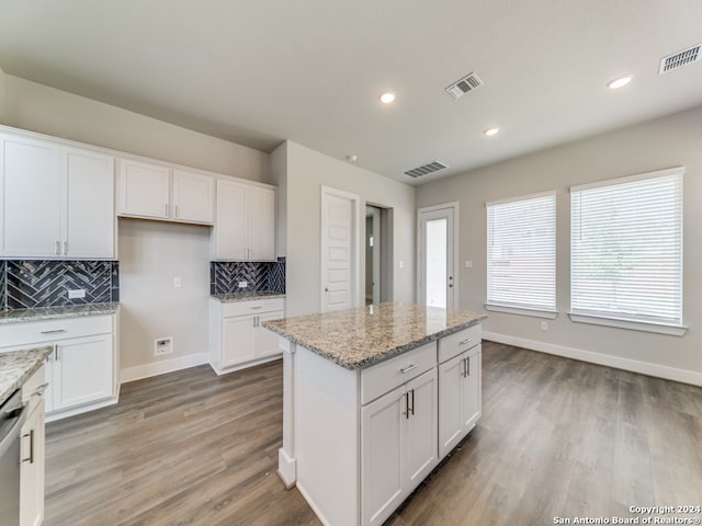 kitchen featuring light stone countertops, a kitchen island, white cabinets, and light hardwood / wood-style flooring