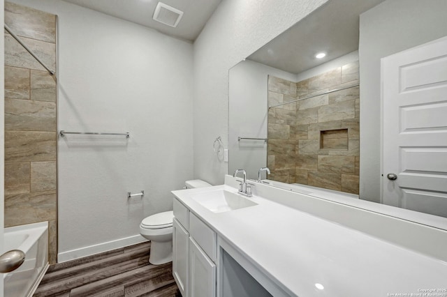 full bathroom with toilet, vanity, tiled shower / bath, and hardwood / wood-style floors