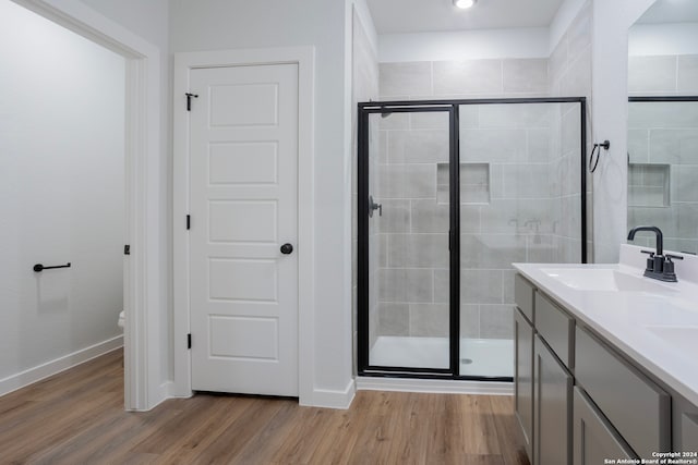 bathroom featuring hardwood / wood-style flooring, toilet, a shower with door, and vanity