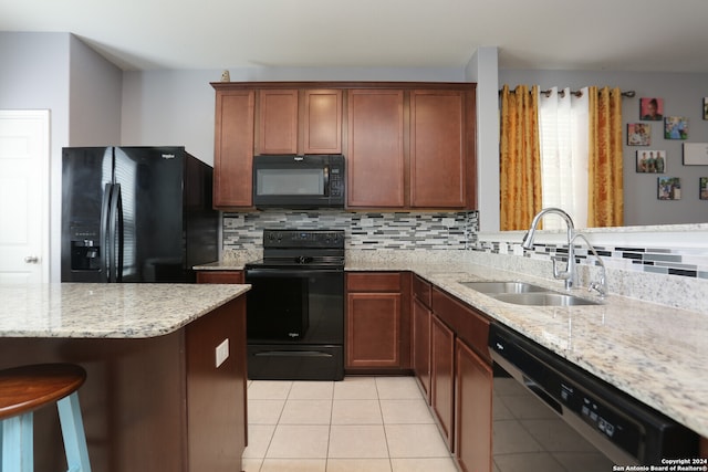 kitchen featuring a breakfast bar, tasteful backsplash, black appliances, and sink