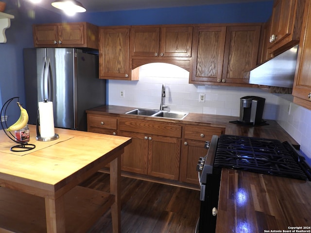 kitchen with sink, tasteful backsplash, gas stove, stainless steel refrigerator, and dark hardwood / wood-style flooring