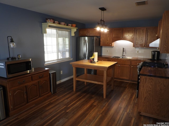 kitchen with sink, dark hardwood / wood-style flooring, stainless steel appliances, decorative light fixtures, and exhaust hood