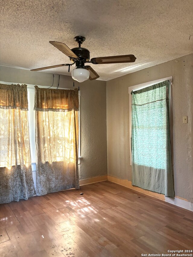 spare room featuring a textured ceiling, wood-type flooring, and ceiling fan