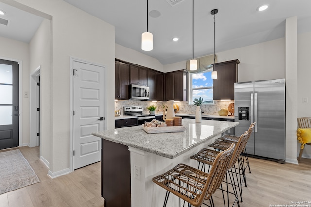 kitchen featuring tasteful backsplash, appliances with stainless steel finishes, light wood-type flooring, dark brown cabinetry, and a center island