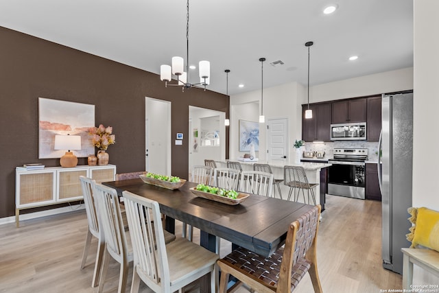 dining space featuring a notable chandelier and light wood-type flooring