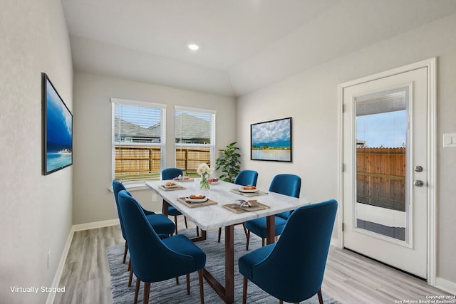 dining room with vaulted ceiling and light wood-type flooring