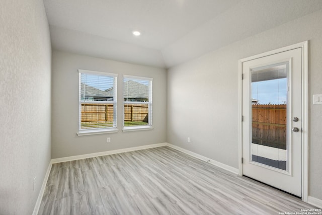 empty room with lofted ceiling and light hardwood / wood-style flooring