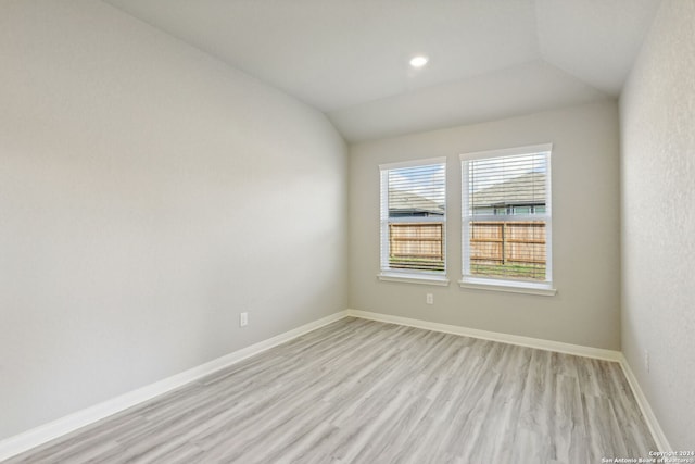 spare room with light hardwood / wood-style flooring and lofted ceiling