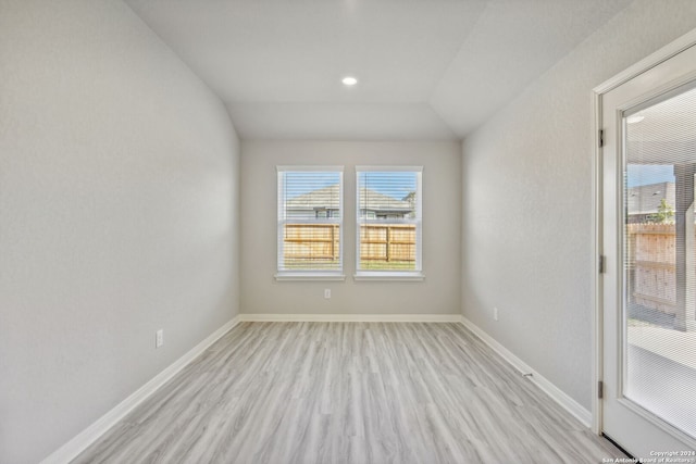 spare room with light hardwood / wood-style flooring and vaulted ceiling