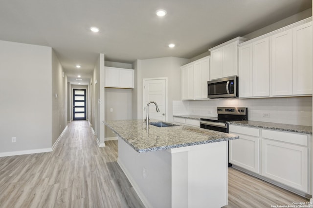 kitchen featuring stainless steel appliances, light stone countertops, sink, and a kitchen island with sink