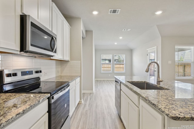 kitchen with light hardwood / wood-style flooring, sink, white cabinetry, appliances with stainless steel finishes, and light stone counters