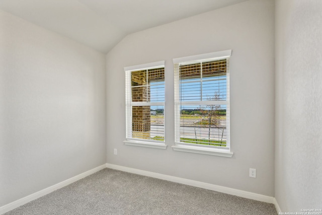 carpeted spare room featuring lofted ceiling