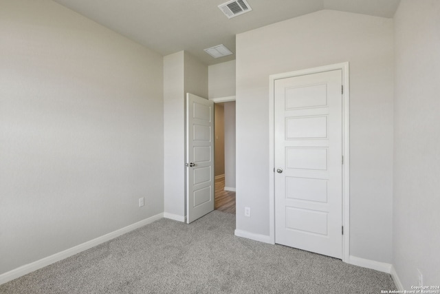 unfurnished bedroom with vaulted ceiling and light carpet