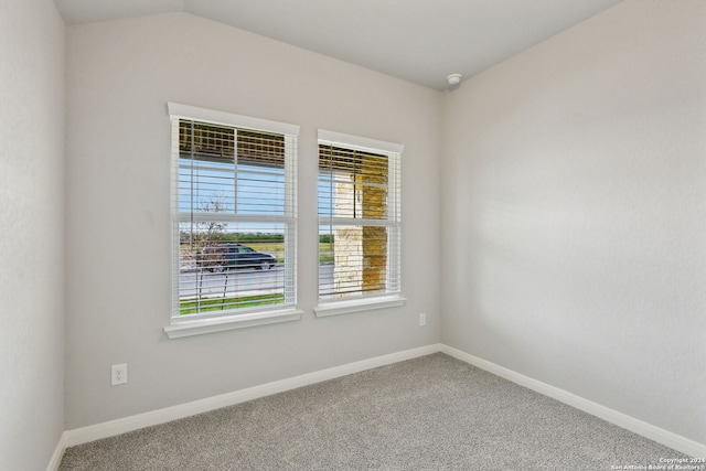 carpeted empty room with vaulted ceiling