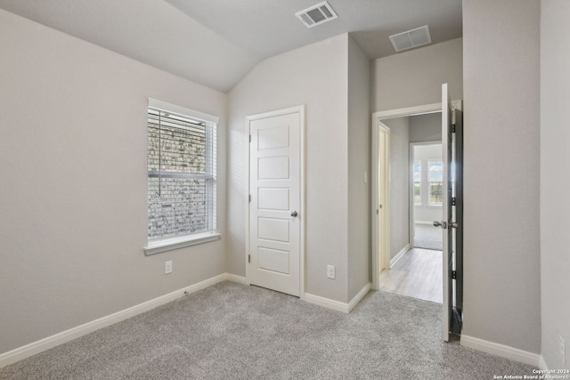 unfurnished bedroom with vaulted ceiling and light colored carpet