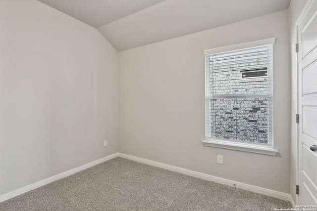 carpeted empty room featuring lofted ceiling