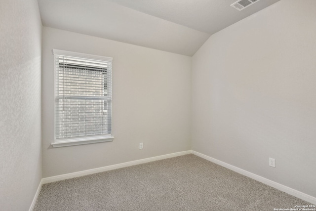 carpeted empty room with vaulted ceiling