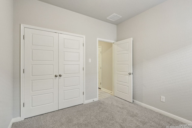 unfurnished bedroom featuring light carpet and a closet