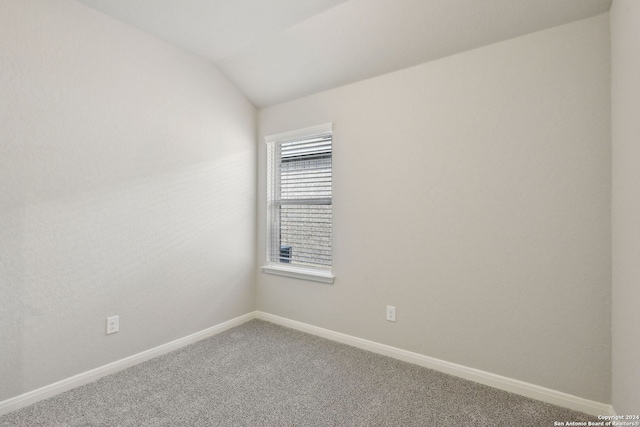 empty room with carpet floors and vaulted ceiling