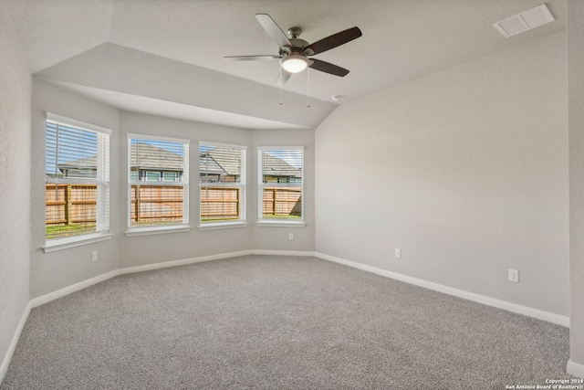 carpeted empty room with a wealth of natural light, vaulted ceiling, and ceiling fan