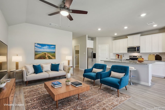 living room featuring lofted ceiling, sink, light hardwood / wood-style flooring, and ceiling fan