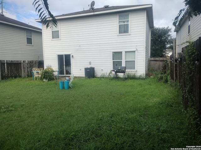 rear view of property featuring central AC and a yard